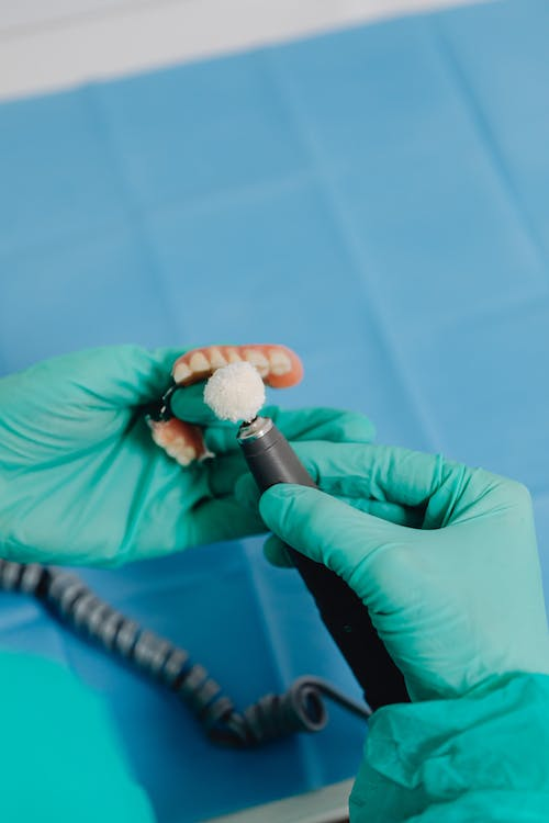 A close-up of a dentist polishing a denture for dental restoration